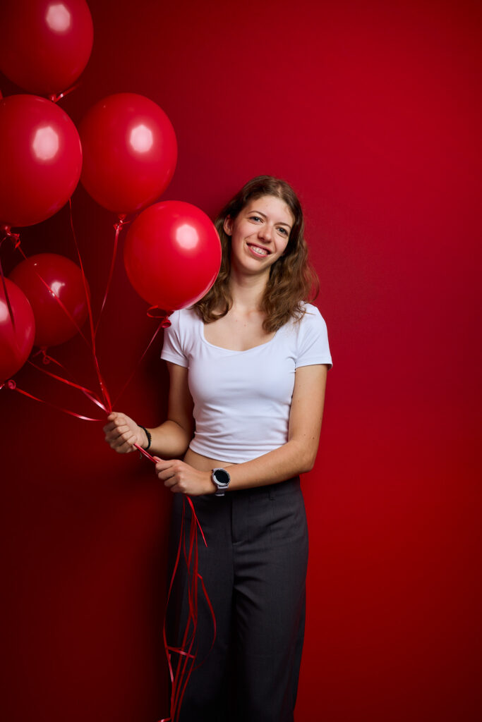 A half-body photo of me, holding red balloons against a red background
